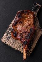 Delicious juicy beef steak on the bone, tomahawk with salt, spices and herbs photo