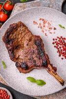 Delicious juicy beef steak on the bone, tomahawk with salt, spices and herbs photo