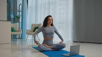 kalmte vrouw yogi zitten lotus houding online yoga klasse met laptop ontspannende muziek- spanning Verlichting mediteren alleen Bij huis vredig vrouw geschiktheid meisje diep ademen zen meditatie praktijk mentaal Gezondheid sport video