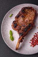 Delicious juicy beef steak on the bone, tomahawk with salt, spices and herbs photo