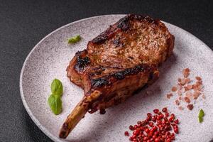 Delicious juicy beef steak on the bone, tomahawk with salt, spices and herbs photo