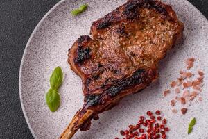 Delicious juicy beef steak on the bone, tomahawk with salt, spices and herbs photo