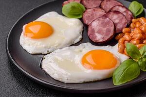 English breakfast with fried eggs, bacon, beans, tomatoes, spices and herbs photo