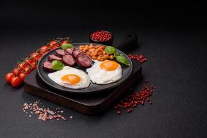 English breakfast with fried eggs, bacon, beans, tomatoes, spices and herbs photo