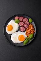 English breakfast with fried eggs, bacon, beans, tomatoes, spices and herbs photo
