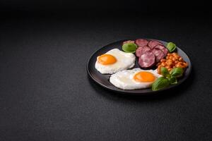 English breakfast with fried eggs, bacon, beans, tomatoes, spices and herbs photo