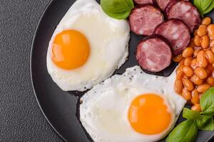 English breakfast with fried eggs, bacon, beans, tomatoes, spices and herbs photo