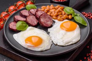 English breakfast with fried eggs, bacon, beans, tomatoes, spices and herbs photo