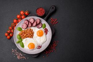 English breakfast with fried eggs, bacon, beans, tomatoes, spices and herbs photo