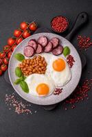 English breakfast with fried eggs, bacon, beans, tomatoes, spices and herbs photo