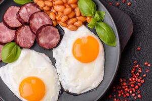 English breakfast with fried eggs, bacon, beans, tomatoes, spices and herbs photo