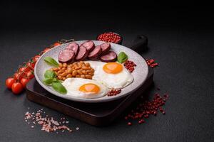 English breakfast with fried eggs, bacon, beans, tomatoes, spices and herbs photo