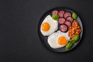 English breakfast with fried eggs, bacon, beans, tomatoes, spices and herbs photo