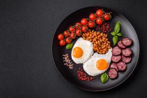 English breakfast with fried eggs, bacon, beans, tomatoes, spices and herbs photo