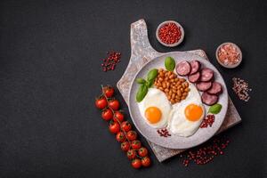 English breakfast with fried eggs, bacon, beans, tomatoes, spices and herbs photo