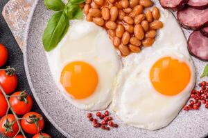 English breakfast with fried eggs, bacon, beans, tomatoes, spices and herbs photo