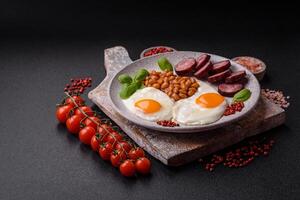 English breakfast with fried eggs, bacon, beans, tomatoes, spices and herbs photo