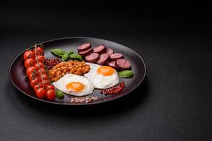 English breakfast with fried eggs, bacon, beans, tomatoes, spices and herbs photo