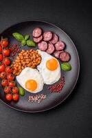 English breakfast with fried eggs, bacon, beans, tomatoes, spices and herbs photo