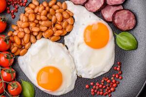 desayuno inglés con huevos fritos, tocino, frijoles, tomates, especias y hierbas foto