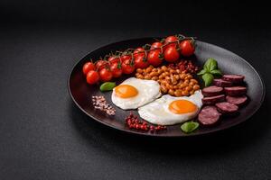 English breakfast with fried eggs, bacon, beans, tomatoes, spices and herbs photo