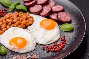 English breakfast with fried eggs, bacon, beans, tomatoes, spices and herbs photo