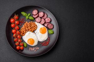 English breakfast with fried eggs, bacon, beans, tomatoes, spices and herbs photo