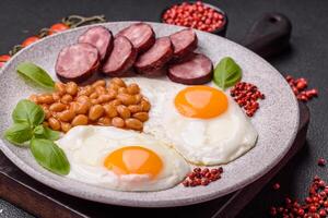 English breakfast with fried eggs, bacon, beans, tomatoes, spices and herbs photo
