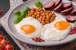 English breakfast with fried eggs, bacon, beans, tomatoes, spices and herbs photo