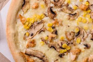 Delicious pizza with corn, cheese, tomatoes and mushrooms, salt, spices and herbs photo