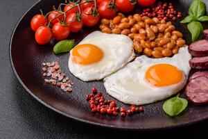 English breakfast with fried eggs, bacon, beans, tomatoes, spices and herbs photo