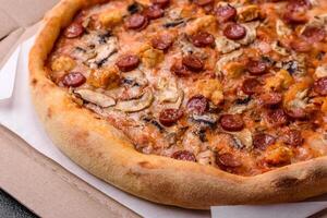 Delicious pizza with sausage, cheese, tomatoes, salt, spices and herbs photo