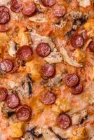 Delicious pizza with sausage, cheese, tomatoes, salt, spices and herbs photo