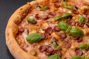Delicious pizza with sausage, cheese, tomatoes, salt, spices and herbs photo