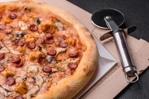 Delicious pizza with sausage, cheese, tomatoes, salt, spices and herbs photo