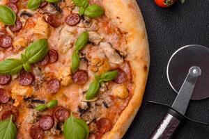 Delicious pizza with sausage, cheese, tomatoes, salt, spices and herbs photo