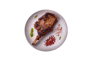 Delicious juicy beef steak on the bone, tomahawk with salt, spices and herbs photo