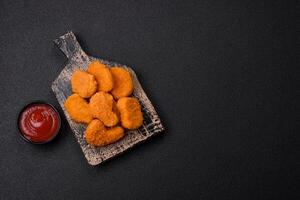 Delicious fresh crispy chicken nuggets on a dark concrete background photo