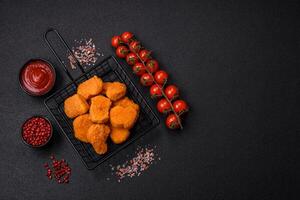 Delicious fresh crispy chicken nuggets on a dark concrete background photo