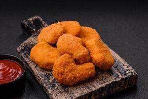 Delicious fresh crispy chicken nuggets on a dark concrete background photo