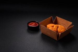 Delicious fresh crispy chicken nuggets on a dark concrete background photo