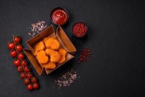 Delicious fresh crispy chicken nuggets on a dark concrete background photo