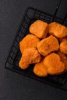 Delicious fresh crispy chicken nuggets on a dark concrete background photo