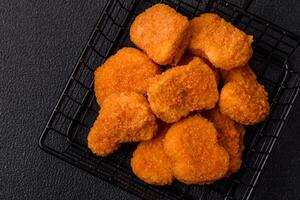 Delicious fresh crispy chicken nuggets on a dark concrete background photo