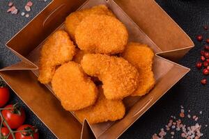 Delicious fresh crispy chicken nuggets on a dark concrete background photo