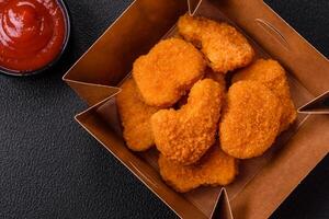 Delicious fresh crispy chicken nuggets on a dark concrete background photo