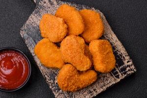 Delicious fresh crispy chicken nuggets on a dark concrete background photo