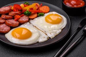 Delicious nutritious breakfast with fried eggs, sausage, steamed vegetables photo
