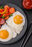 Delicious nutritious breakfast with fried eggs, sausage, steamed vegetables photo