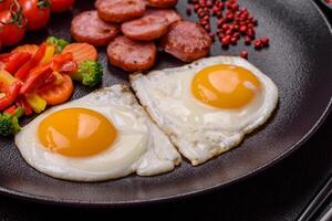 Delicious nutritious breakfast with fried eggs, sausage, steamed vegetables photo